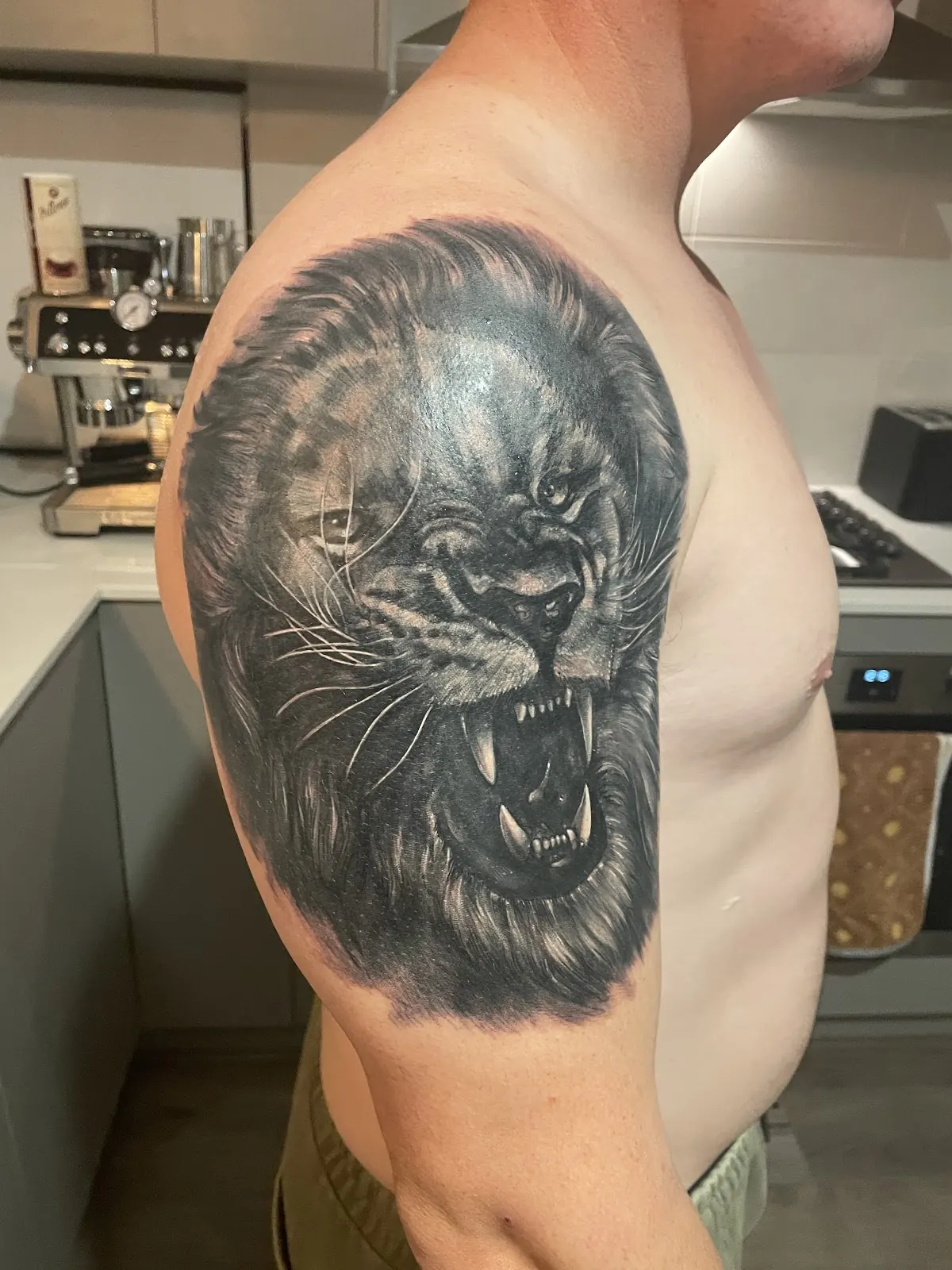 Black and grey realism lion tattoo on a shoulder, by Kris Barnas