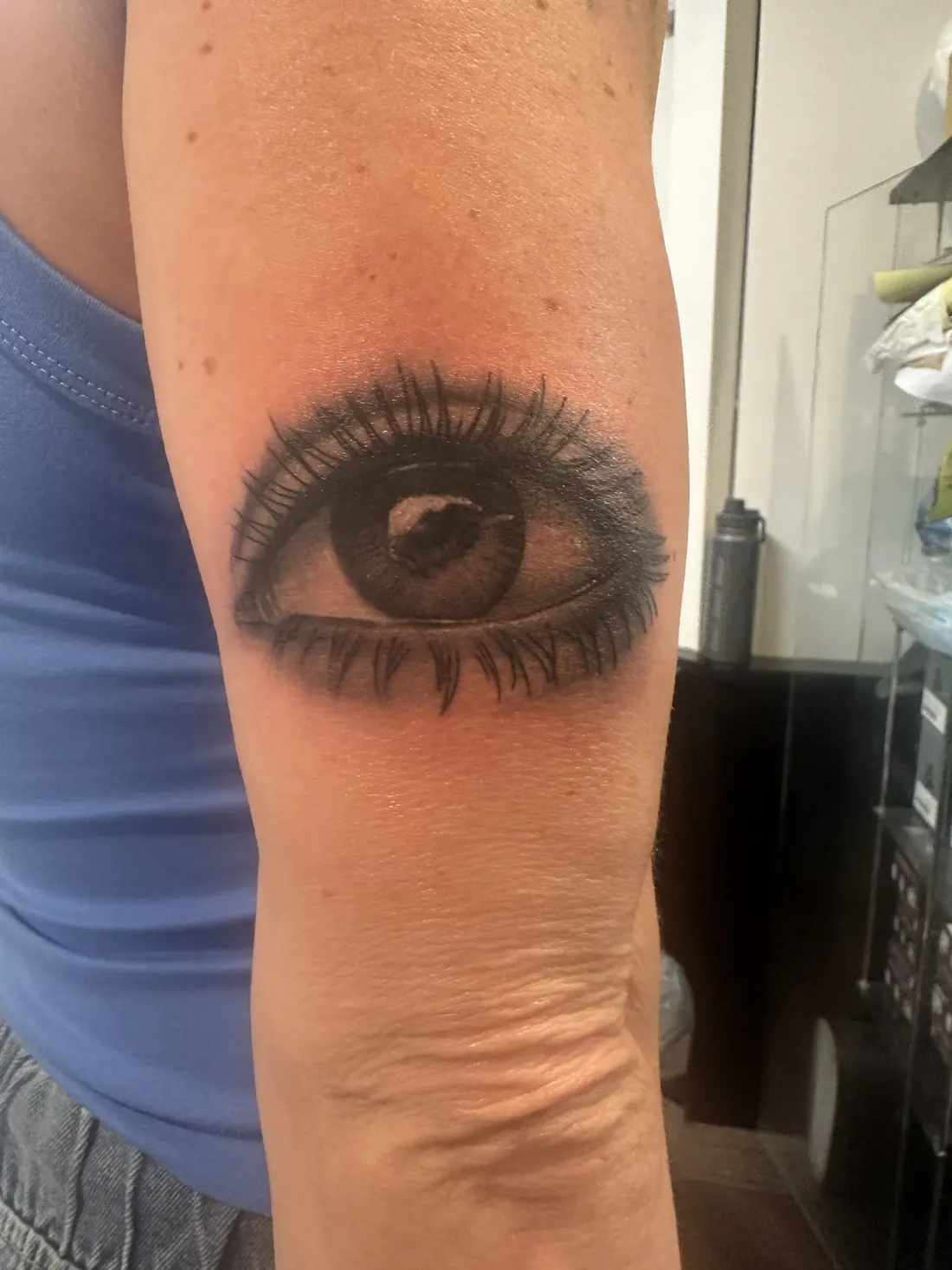 Realistic black and grey eye tattoo on a forearm